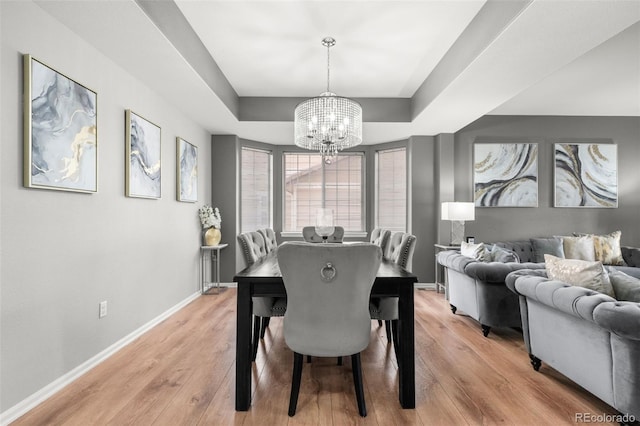 24880 E Euclid Pl, Aurora, CO 80016 - dining space featuring baseboards, a notable chandelier, a tray ceiling, and light wood-style flooring