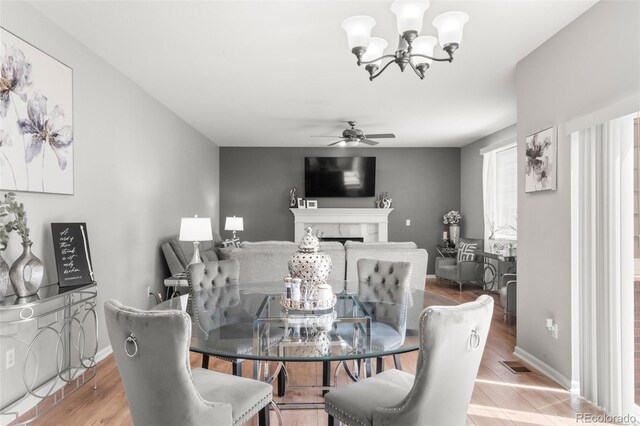 24880 E Euclid Pl, Aurora, CO 80016 - dining room featuring visible vents, light wood-type flooring, baseboards, a fireplace, and ceiling fan with notable chandelier