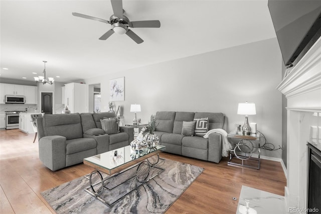 24880 E Euclid Pl, Aurora, CO 80016 - living room featuring light wood-type flooring, baseboards, recessed lighting, and ceiling fan with notable chandelier