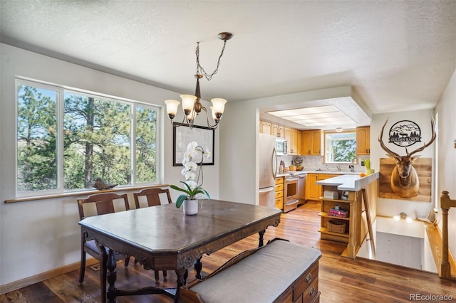 dining space featuring light wood-type flooring, a textured ceiling, and an inviting chandelier