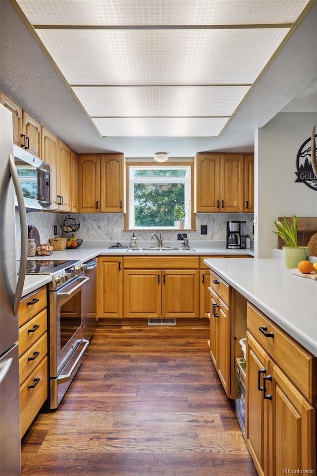 kitchen with backsplash, sink, appliances with stainless steel finishes, and dark wood-type flooring