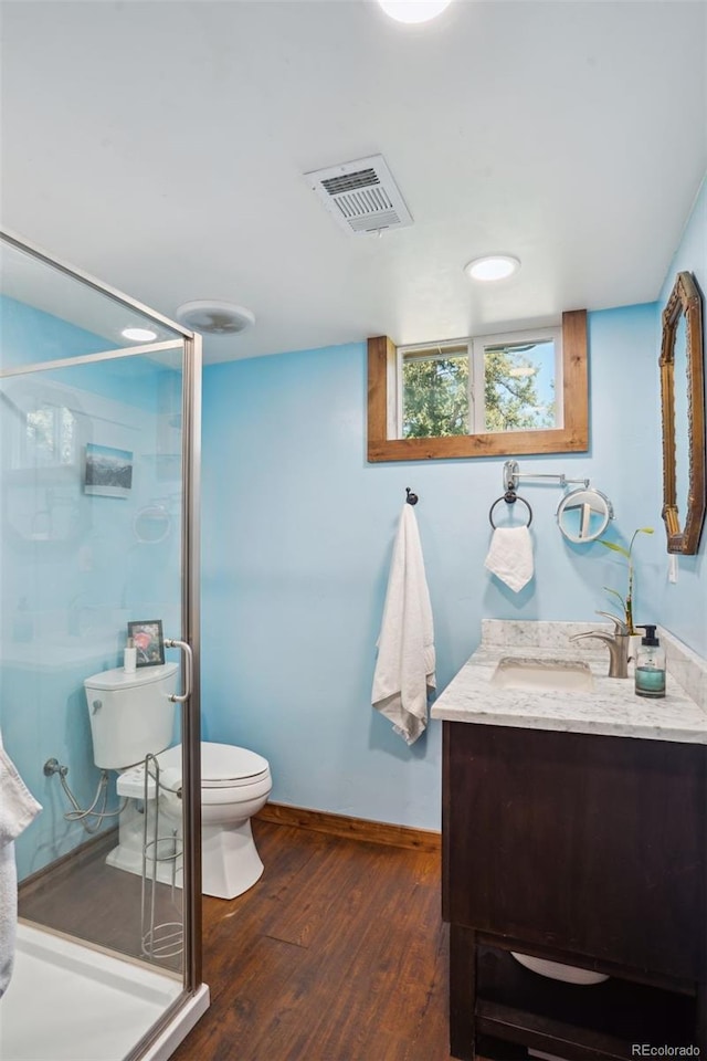 bathroom with wood-type flooring, vanity, toilet, and walk in shower