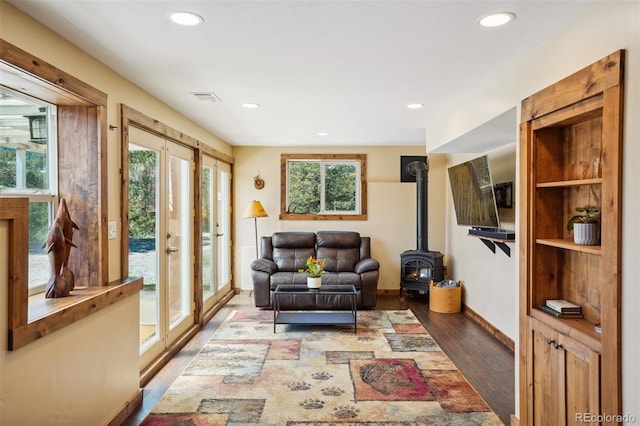 sitting room featuring a wood stove, french doors, wood-type flooring, and plenty of natural light