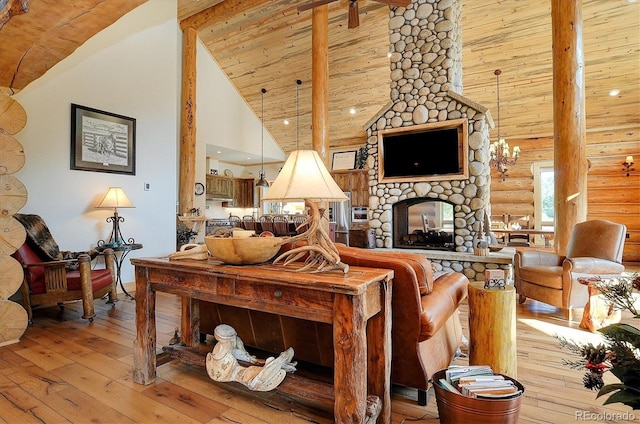 living room featuring log walls, light hardwood / wood-style flooring, a stone fireplace, beam ceiling, and high vaulted ceiling