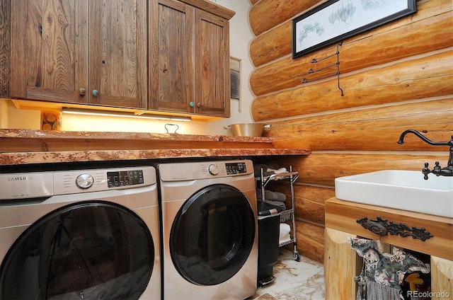 laundry area featuring wood walls, cabinets, independent washer and dryer, and sink