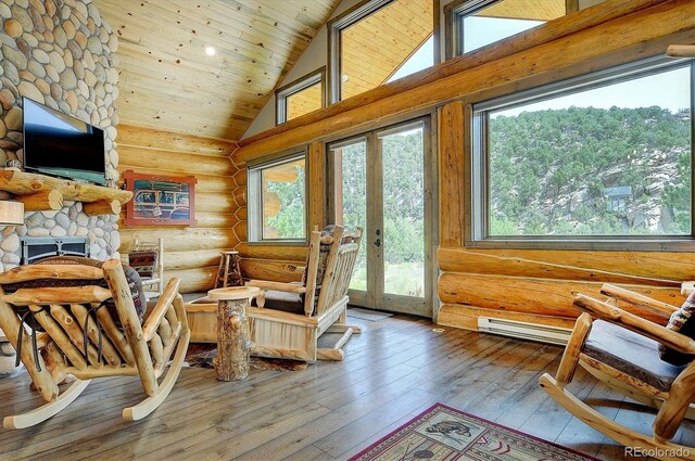 living room featuring high vaulted ceiling, hardwood / wood-style floors, a stone fireplace, wooden ceiling, and log walls