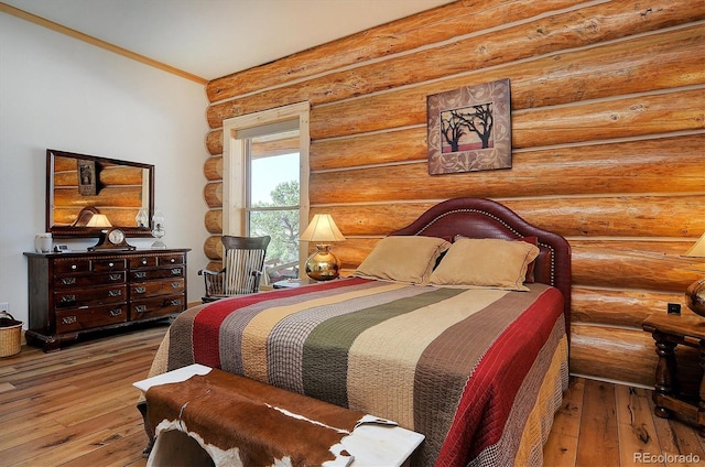 bedroom with hardwood / wood-style floors and log walls