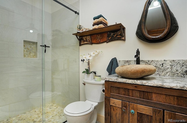 bathroom featuring a shower with shower door, toilet, and vanity