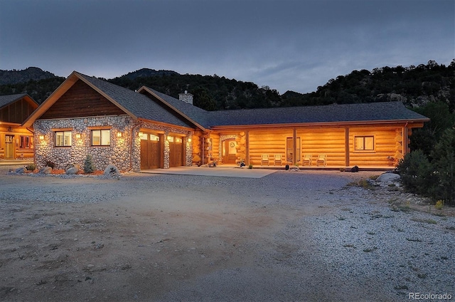 view of front of home featuring a garage, a chimney, driveway, and log exterior