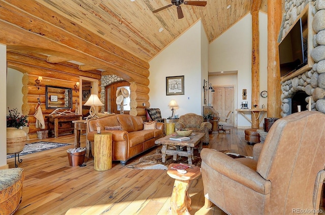 living room with hardwood / wood-style flooring, log walls, wooden ceiling, ceiling fan, and a stone fireplace