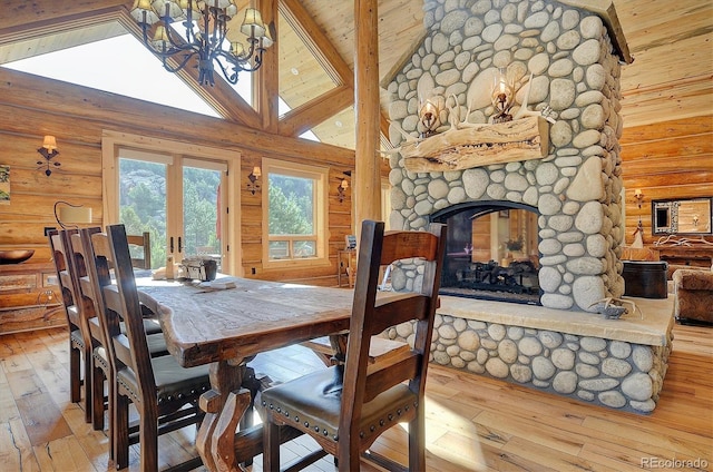 dining space with a stone fireplace, wood-type flooring, wood ceiling, and log walls