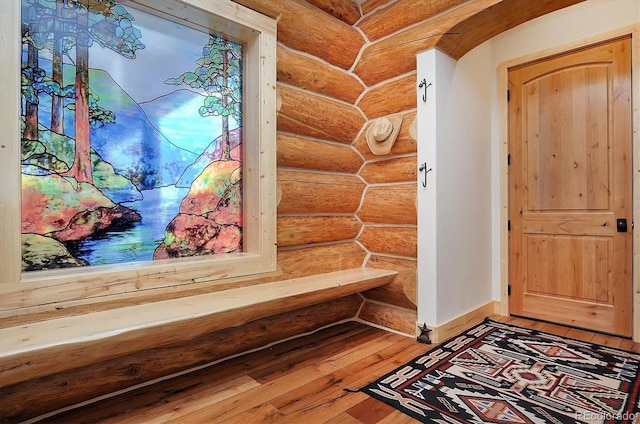 mudroom featuring log walls and wood-type flooring