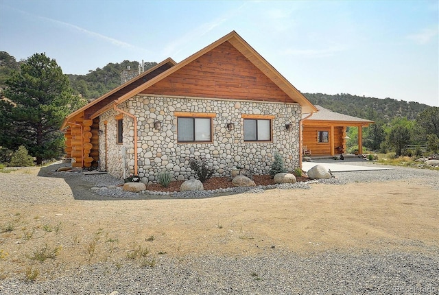view of side of property with stone siding and a chimney