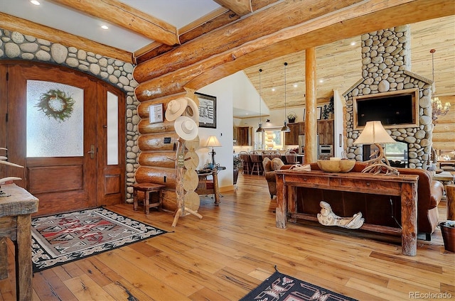 entrance foyer featuring beamed ceiling, hardwood / wood-style floors, rustic walls, and a fireplace