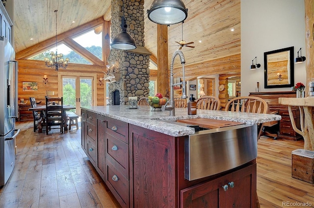 kitchen featuring light wood finished floors, high vaulted ceiling, stainless steel fridge with ice dispenser, wooden ceiling, and rustic walls
