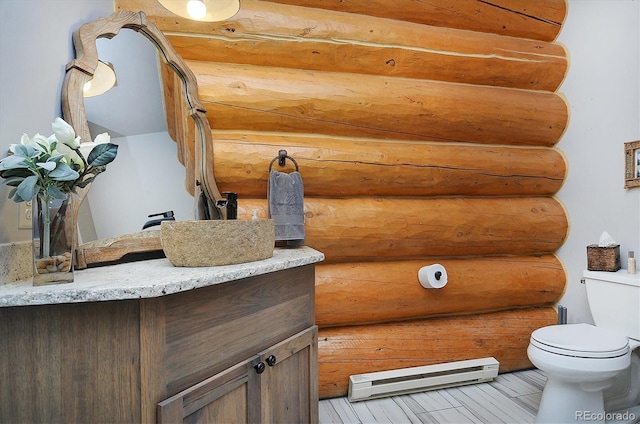 bathroom featuring a baseboard radiator, toilet, rustic walls, and vanity