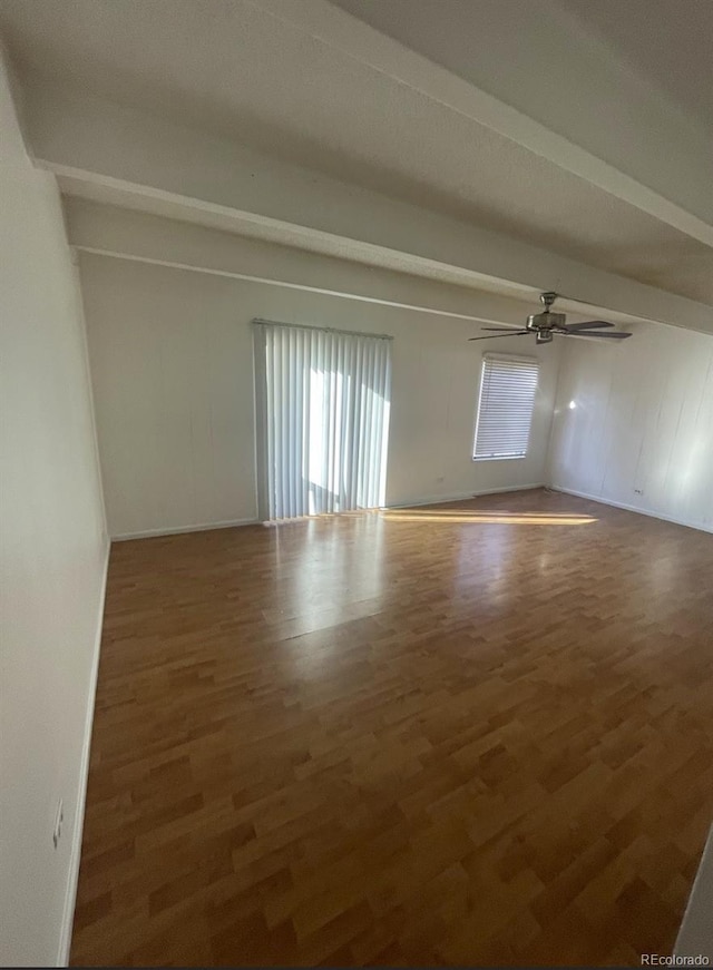 spare room featuring ceiling fan, dark hardwood / wood-style floors, and beam ceiling