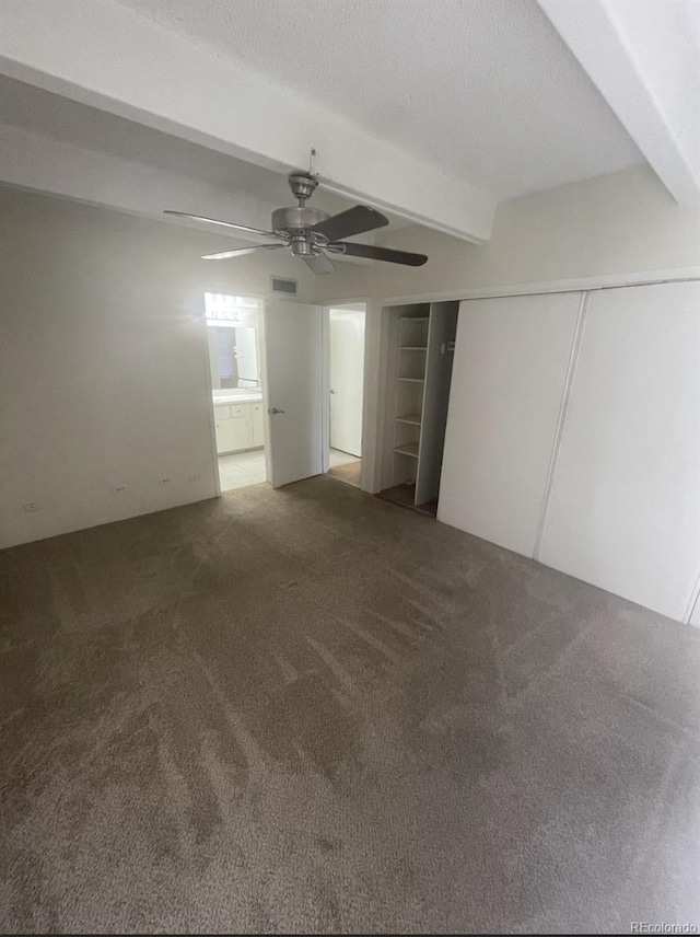 unfurnished bedroom featuring visible vents, carpet floors, beam ceiling, ceiling fan, and a textured ceiling