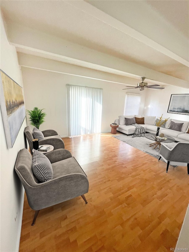 living area with beam ceiling and wood finished floors