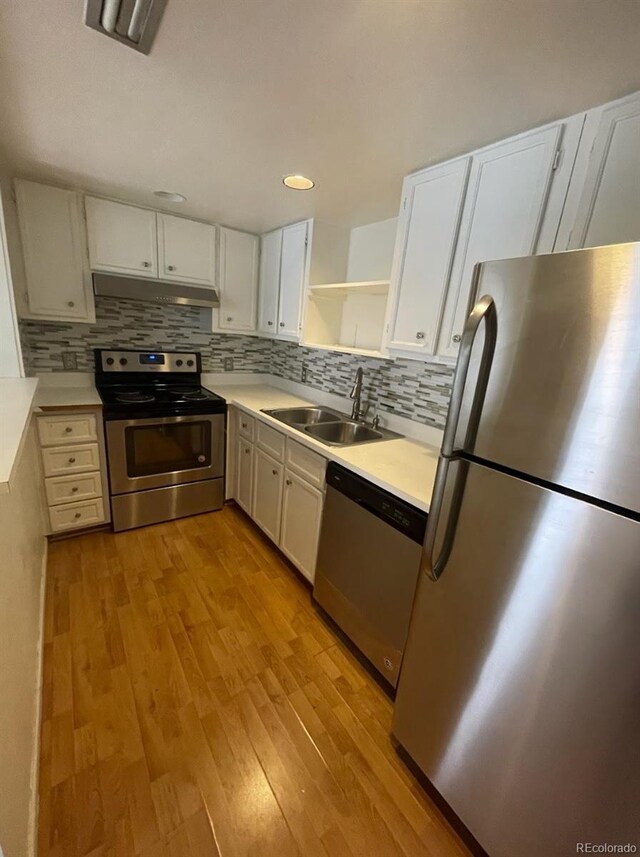 kitchen featuring open shelves, light wood-style flooring, a sink, stainless steel appliances, and under cabinet range hood