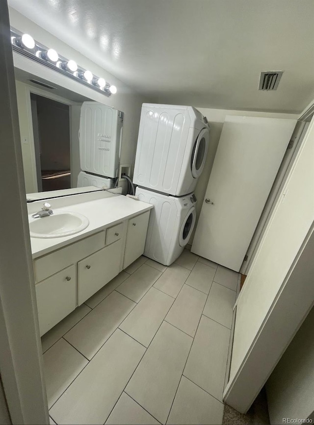 bathroom featuring vanity, tile patterned floors, visible vents, and stacked washing maching and dryer