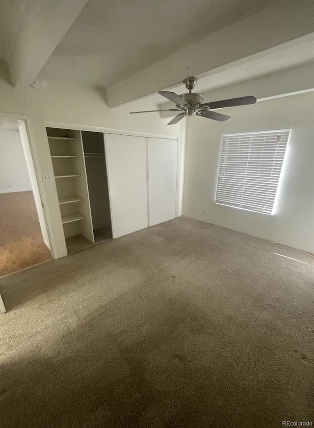 unfurnished bedroom featuring beam ceiling, a ceiling fan, a closet, and carpet floors