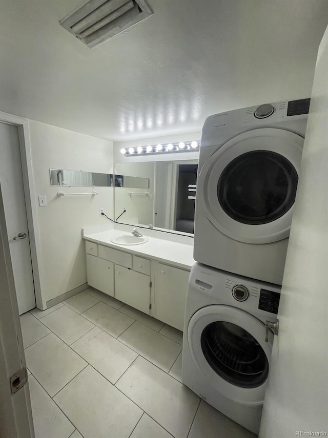 9995 E Harvard Ave Unit 177, Denver, CO 80231 - washroom featuring stacked washer and clothes dryer, a sink, light tile patterned floors, and baseboards