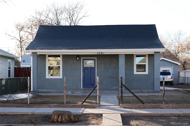 bungalow-style house with a fenced front yard, a shingled roof, a gate, and stucco siding