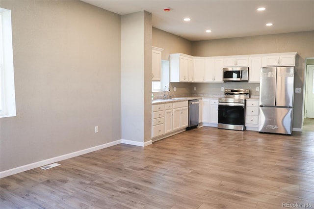 kitchen featuring light wood finished floors, stainless steel appliances, a sink, and light countertops