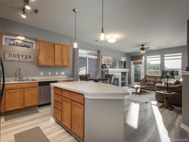 kitchen featuring pendant lighting, dishwasher, sink, ceiling fan, and a kitchen island