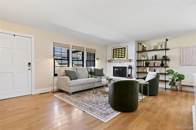 living area featuring visible vents, baseboards, light wood-style floors, and a fireplace