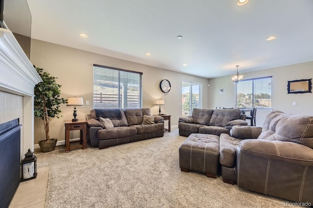 carpeted living room with a tiled fireplace and an inviting chandelier