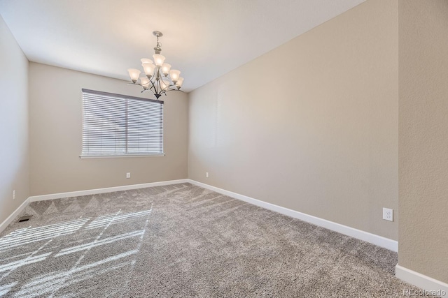 carpeted empty room featuring an inviting chandelier