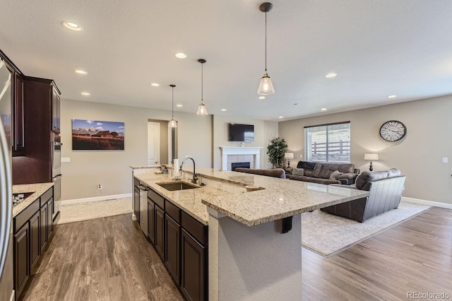 kitchen with sink, a fireplace, a spacious island, light hardwood / wood-style floors, and decorative light fixtures