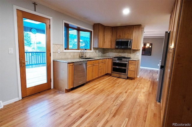 kitchen with backsplash, crown molding, appliances with stainless steel finishes, and a sink