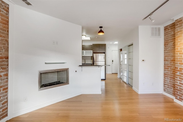 kitchen with light wood finished floors, dark countertops, visible vents, a peninsula, and stainless steel refrigerator