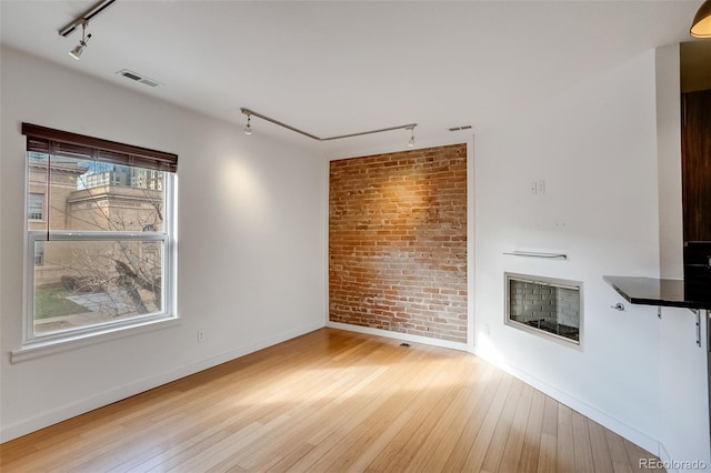 unfurnished living room featuring hardwood / wood-style flooring, visible vents, and track lighting