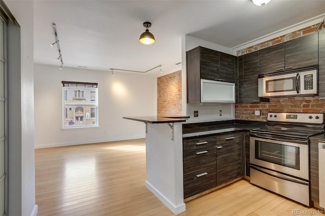 kitchen with dark countertops, light wood-style floors, appliances with stainless steel finishes, and dark brown cabinets