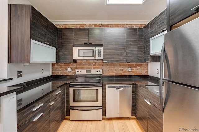 kitchen with dark brown cabinetry, decorative backsplash, light wood-style flooring, modern cabinets, and stainless steel appliances