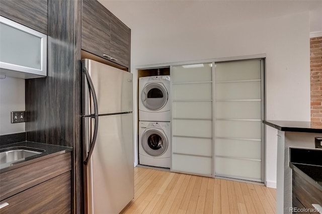 kitchen with stacked washer and dryer, freestanding refrigerator, dark stone countertops, modern cabinets, and light wood-type flooring