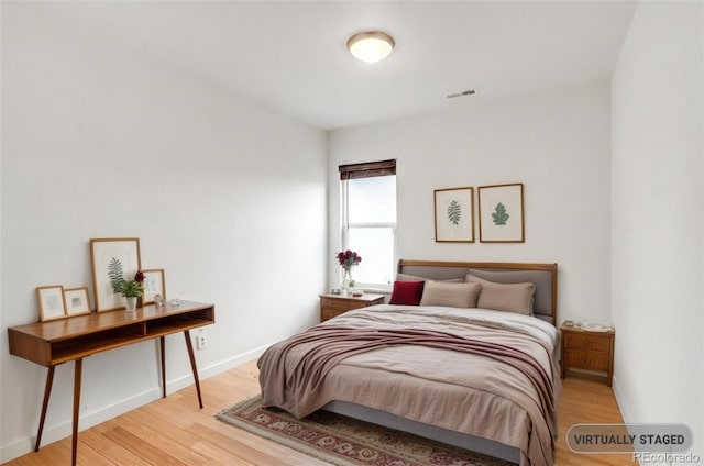 bedroom featuring light wood-type flooring, visible vents, and baseboards