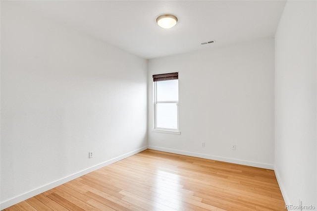 unfurnished room featuring light wood-type flooring, visible vents, and baseboards