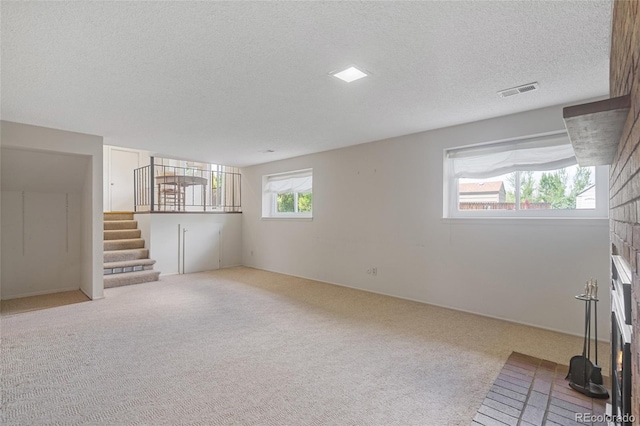 unfurnished living room with stairs, carpet flooring, and a textured ceiling