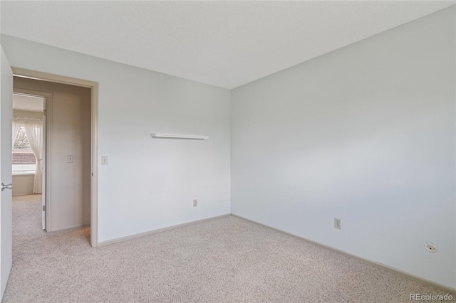 spare room with light carpet and baseboards