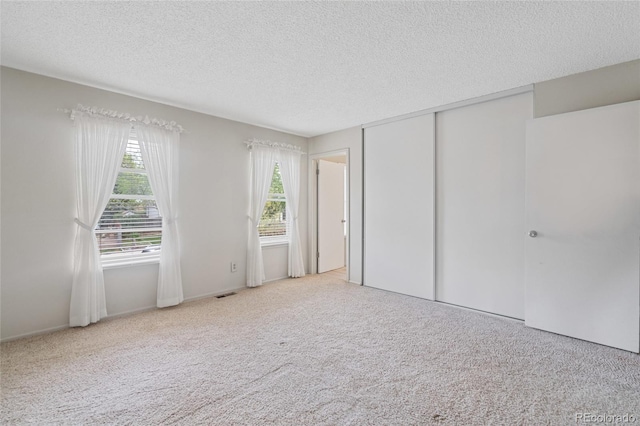 unfurnished bedroom featuring a textured ceiling, carpet flooring, and a closet