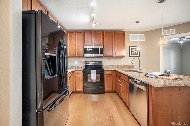 1144 Rockhurst Dr Unit 105, Highlands Ranch, CO 80129 - kitchen featuring black appliances, a sink, light wood-style floors, a peninsula, and brown cabinets
