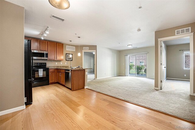 1144 Rockhurst Dr Unit 105, Highlands Ranch, CO 80129 - kitchen with black appliances, brown cabinetry, a peninsula, open floor plan, and light wood-style floors
