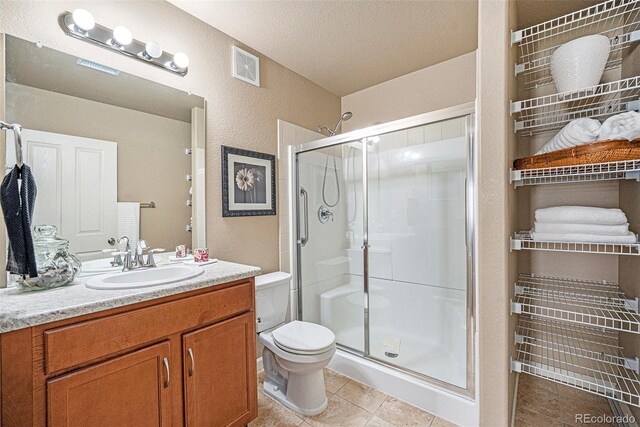 1144 Rockhurst Dr Unit 105, Highlands Ranch, CO 80129 - bathroom featuring a stall shower, toilet, tile patterned floors, a textured wall, and vanity