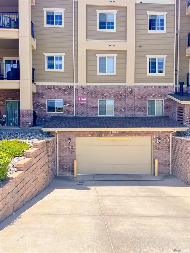 1144 Rockhurst Dr Unit 105, Highlands Ranch, CO 80129 - back of property with brick siding, a garage, and driveway