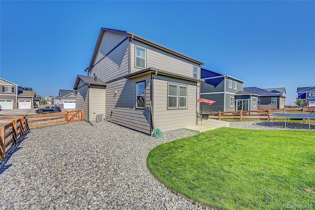 rear view of property with a trampoline, a lawn, a patio, and central air condition unit